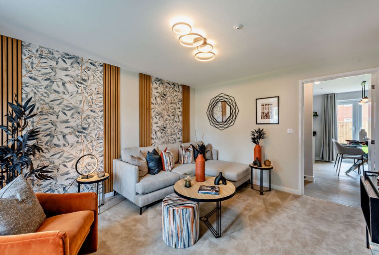 A living room with a sectional sofa, coffee table, and decorative wallpaper.