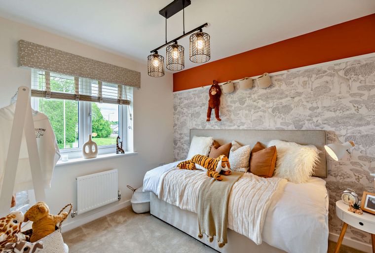 A children's bedroom with a bed, stuffed animals, and safari-themed wallpaper.