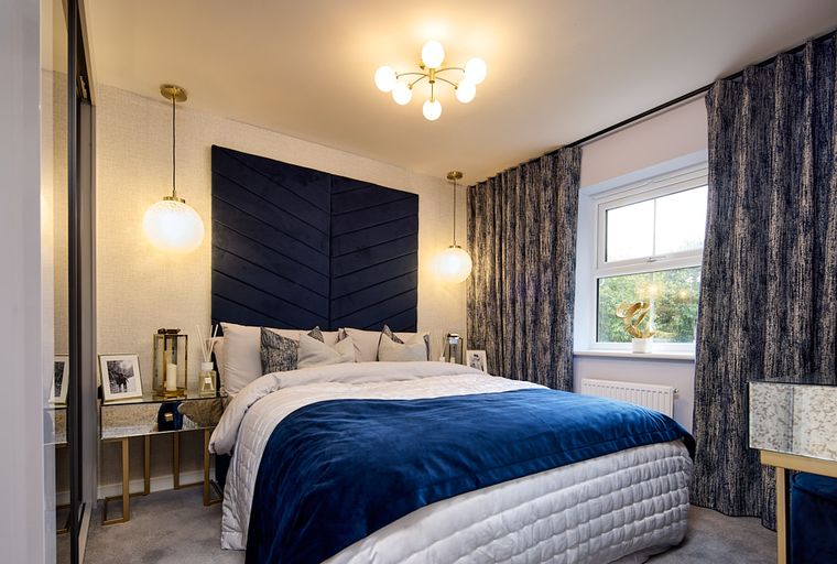 A bedroom with a bed, headboard, and pendant lights.