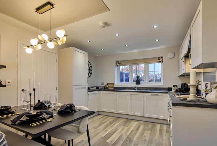 A dining area and kitchen with a table set for dinner and white cabinets.