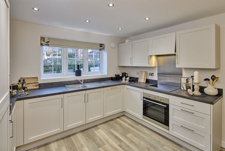 A modern kitchen with cream cabinets, a double sink, and an oven.