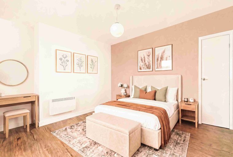A bedroom with a bed, nightstands, a vanity, and artwork.