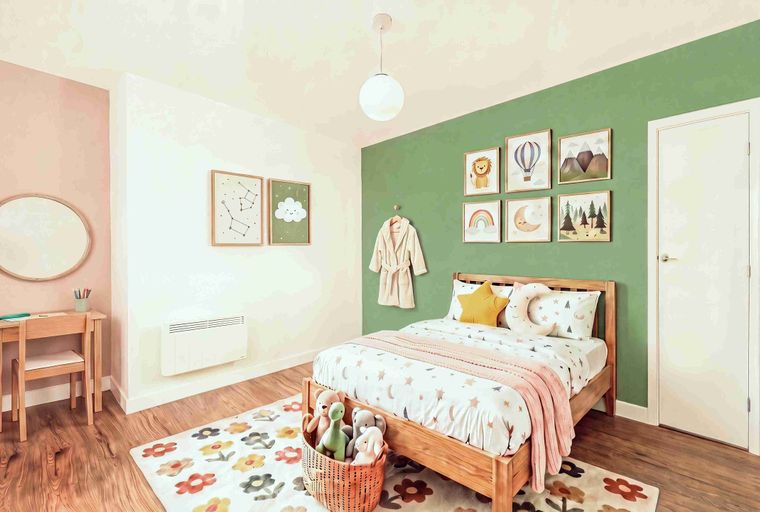 A child's bedroom with a bed, artwork, and stuffed animals.