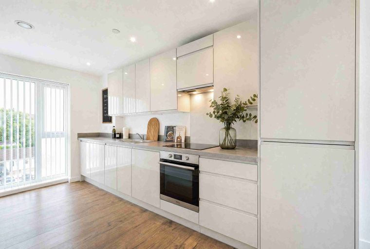 A modern kitchen with white cabinets, a sink, an oven, and a stovetop.
