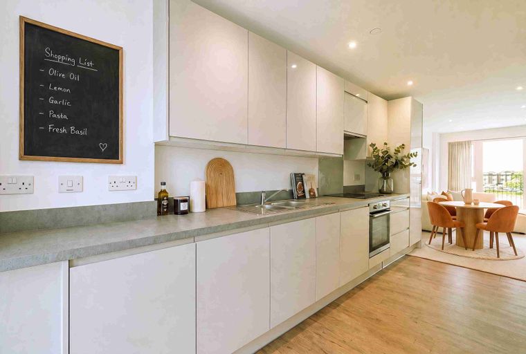 A modern kitchen with sleek cabinetry, a grey countertop, and a chalkboard shopping list.