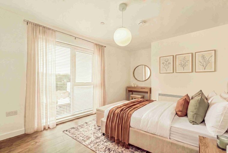 A bedroom with a bed, curtains, and artwork.