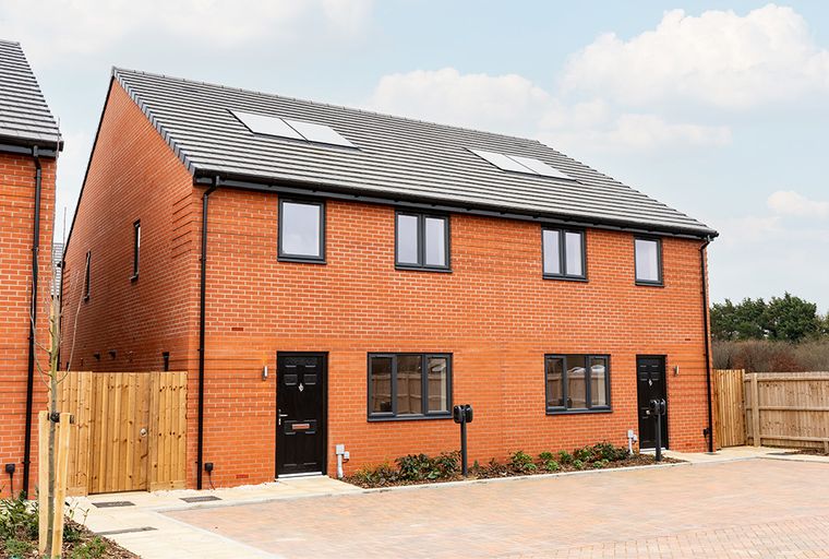 A modern red brick house with grey windows and a tiled roof.
