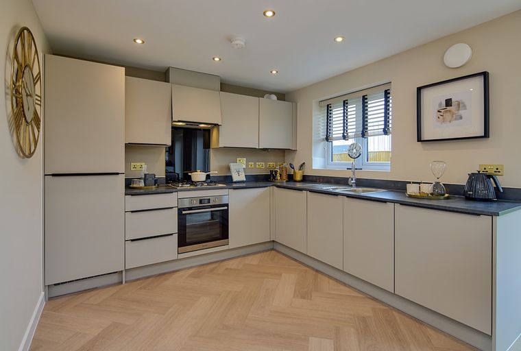 A modern kitchen with light-colored cabinets, a dark countertop, and a gas hob.