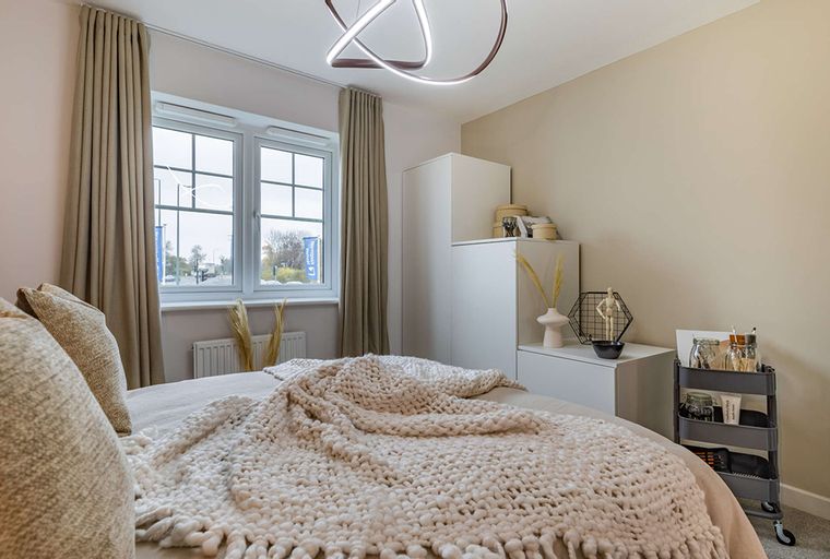 A bedroom with a bed, window, and wardrobe.