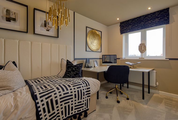 A bedroom with a bed, desk, and window.
