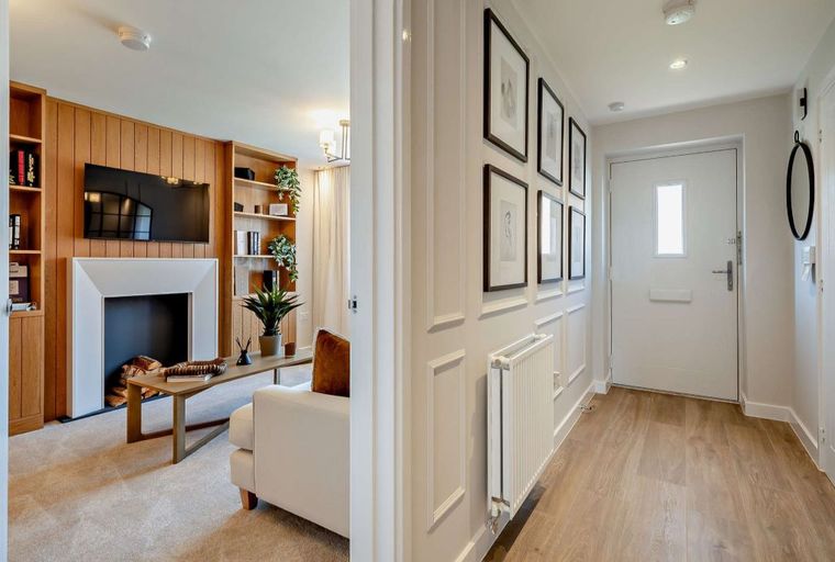 A hallway and living room with a fireplace, television, and furniture.