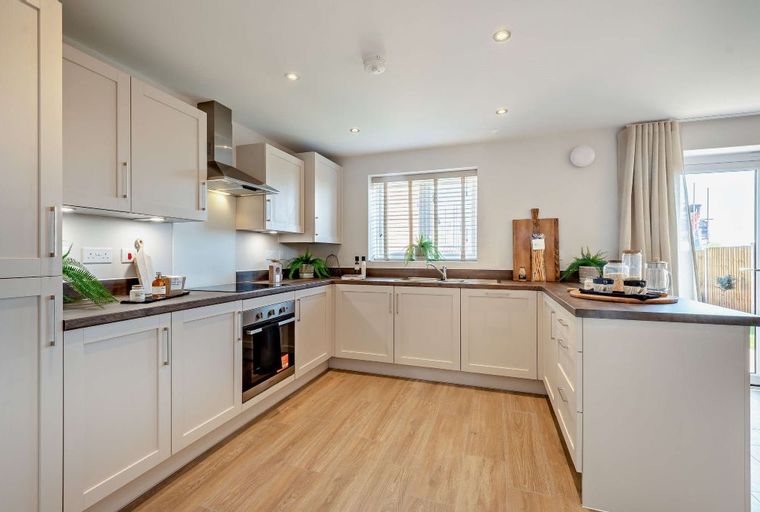 A modern kitchen with white cabinets, a built-in oven, and a window.