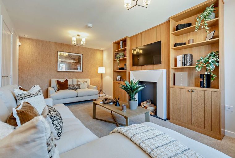 A living room with sofas, a coffee table, a fireplace, and a built-in bookshelf.