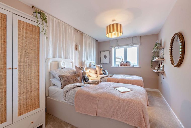 A bedroom with two twin beds, a wardrobe, and decorative shelves.