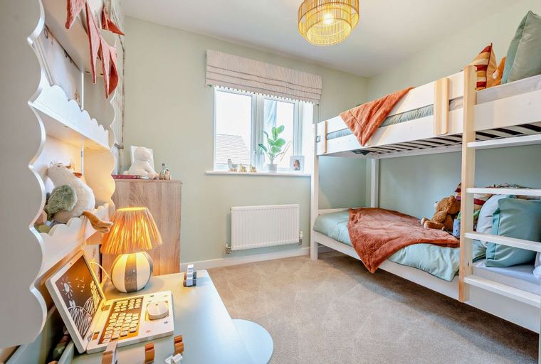 A children's bedroom with bunk beds, a desk, and shelves.