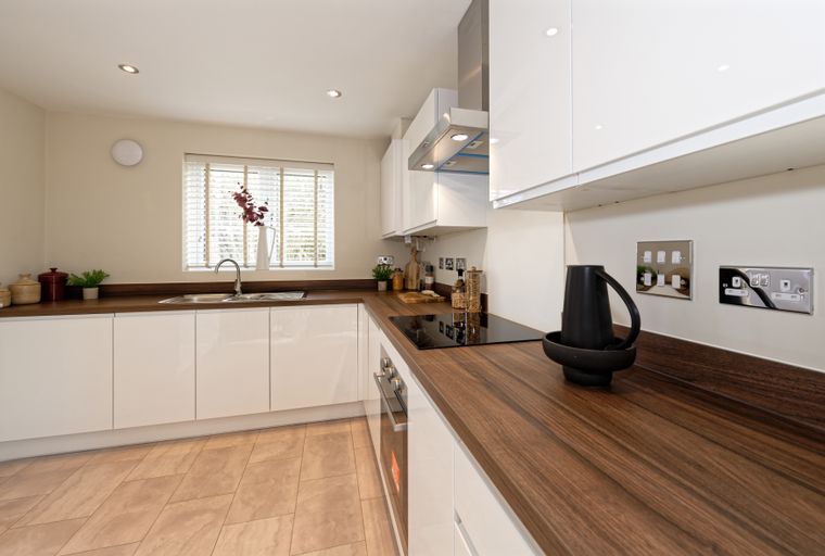 A modern kitchen with white cabinets, a wooden countertop, and a sink.