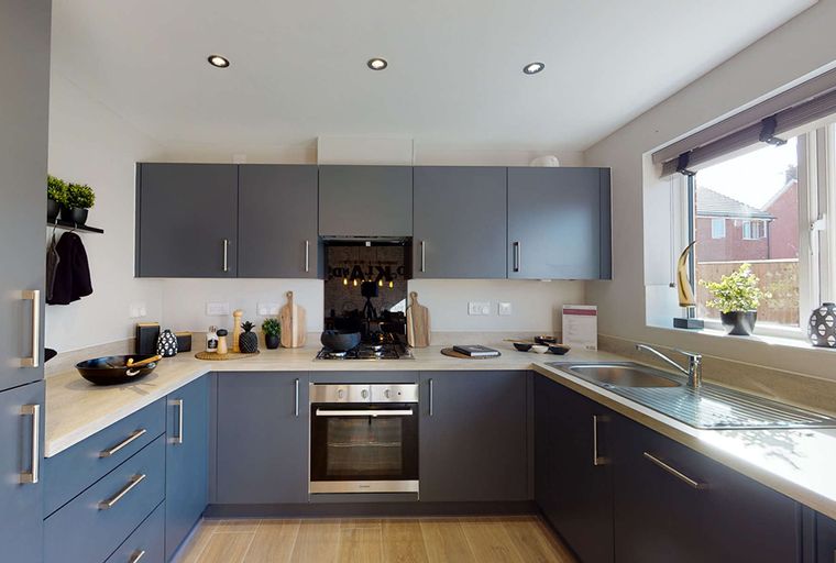 A modern kitchen with dark gray cabinets, a stainless steel oven, and a sink.