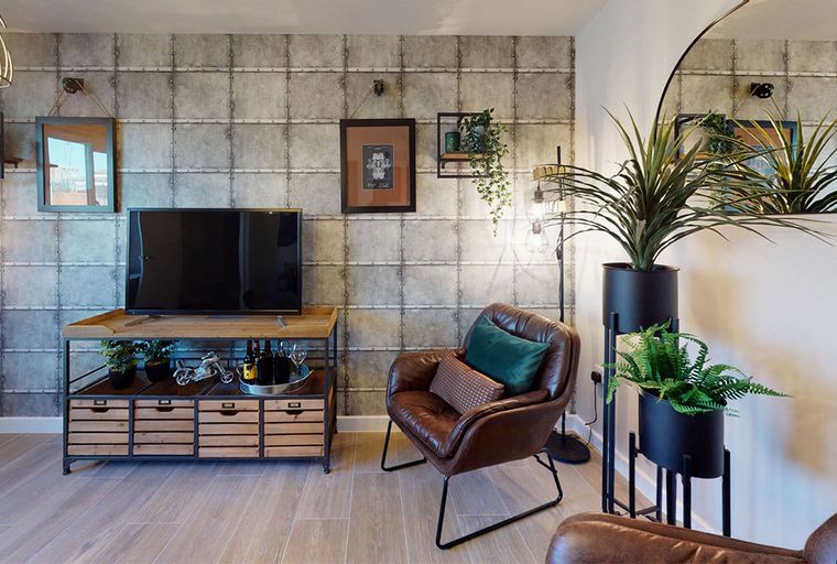 A living room with a television, armchair, and plants.