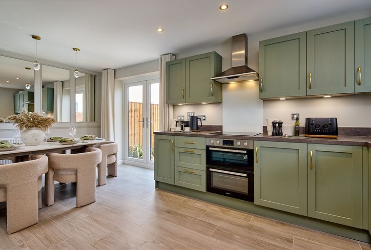 A kitchen and dining area with sage green cabinets, a dining table, and French doors.