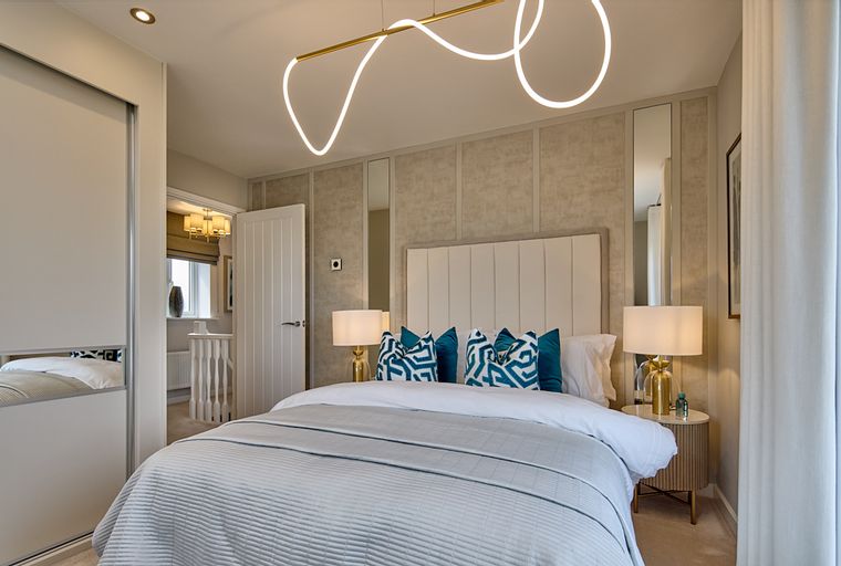 A bedroom with a bed, headboard, bedside tables, lamps, pillows, and a sliding door wardrobe.