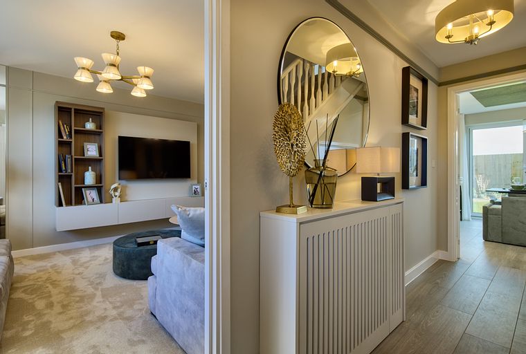 A hallway and living room with a television, sofa, and decorative items.