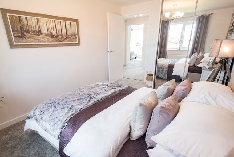 A bedroom with a bed, pillows, and a large framed artwork on the wall.