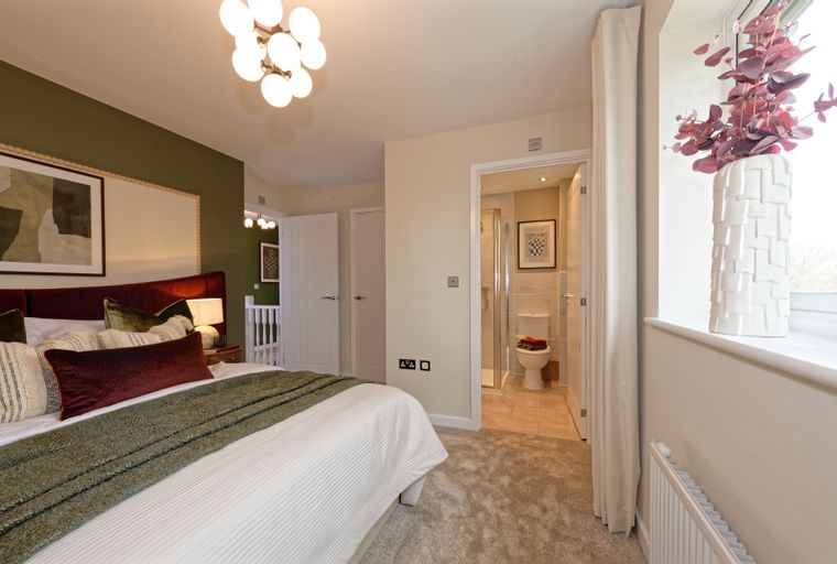 A bedroom with a bed, pillows, a throw blanket, and an en-suite bathroom.