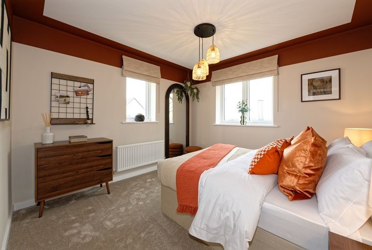 A bedroom with a bed, dresser, and windows.