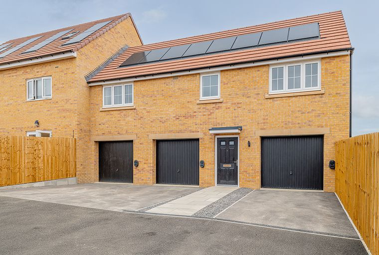 A modern yellow brick house with multiple garages and solar panels on the roof.