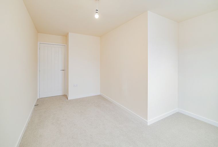 A room with a white door and carpeted floor.