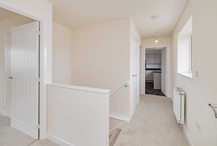 A hallway with doors, a staircase, and a window.
