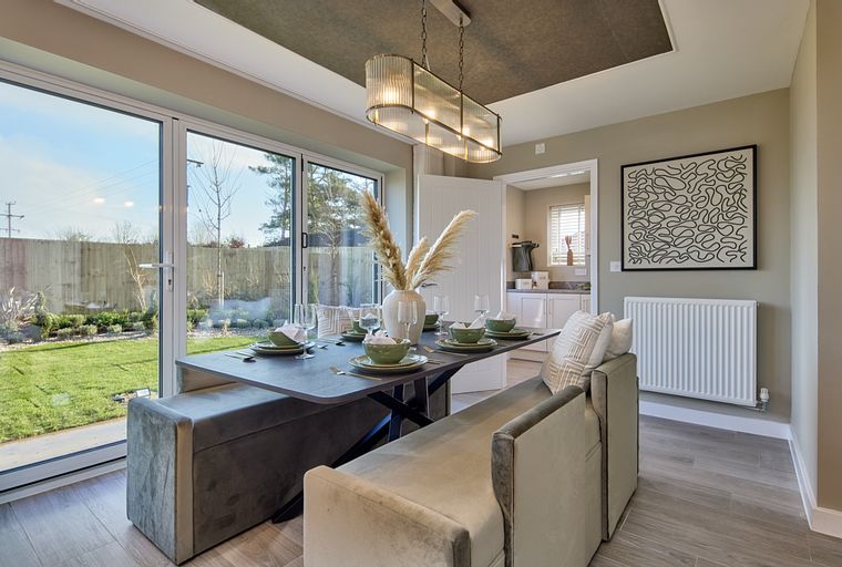 A dining area with a table, benches, and large glass doors leading to a garden.
