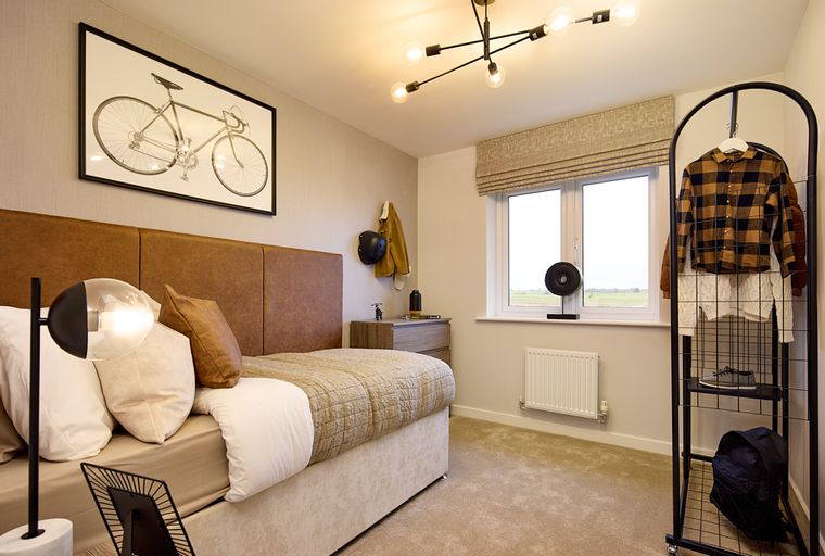 A bedroom with a bed, a bicycle print, a window, and a clothing rack.