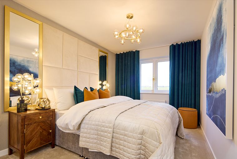 A bedroom with a bed, pillows, curtains, and a chandelier.