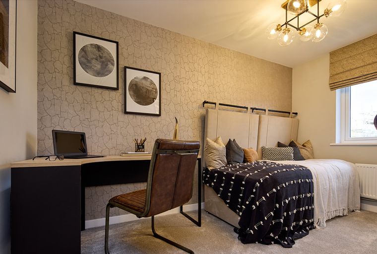 A bedroom with a bed, a desk, and a chair.
