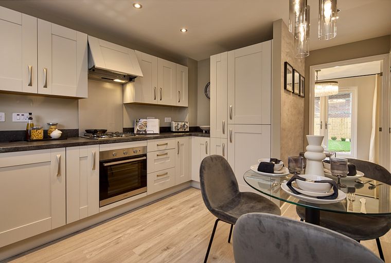 A modern kitchen and dining area with light-colored cabinets, a glass-top dining table, and comfortable chairs.