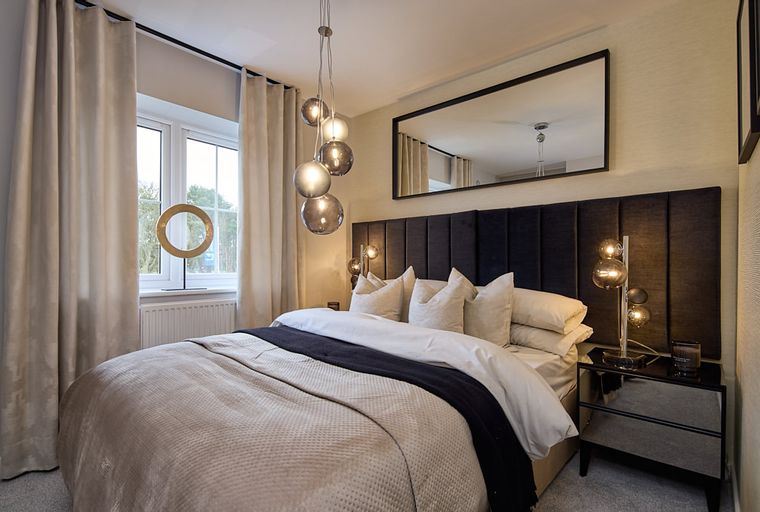 A bedroom with a bed, headboard, curtains, and a bedside lamp.