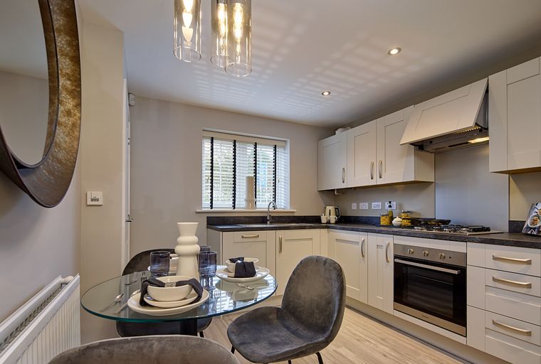 A modern kitchen and dining area with a glass table and chairs.