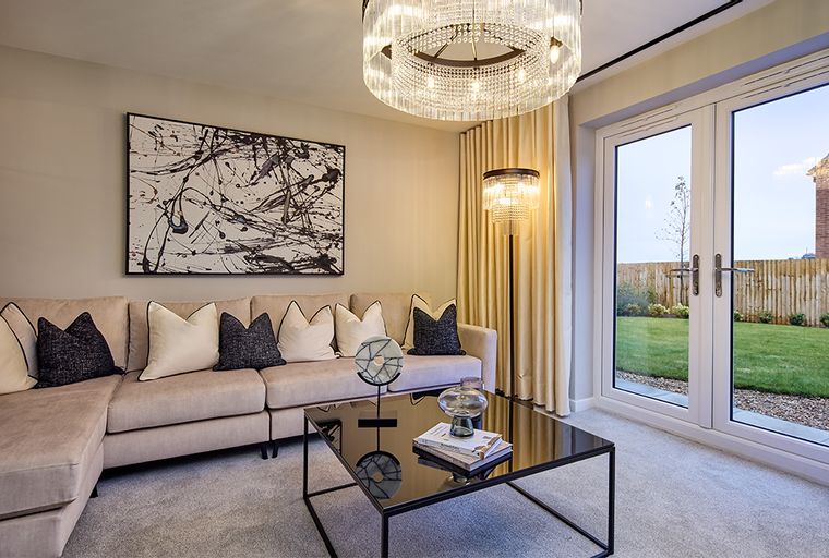 A living room with a sectional sofa, coffee table, abstract art, and double doors leading to a backyard.