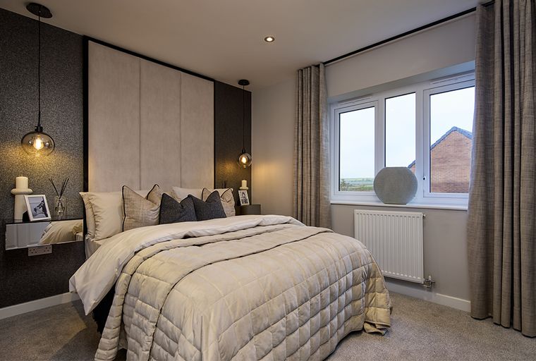 A bedroom with a bed, headboard, pendant lights, and a window with curtains.