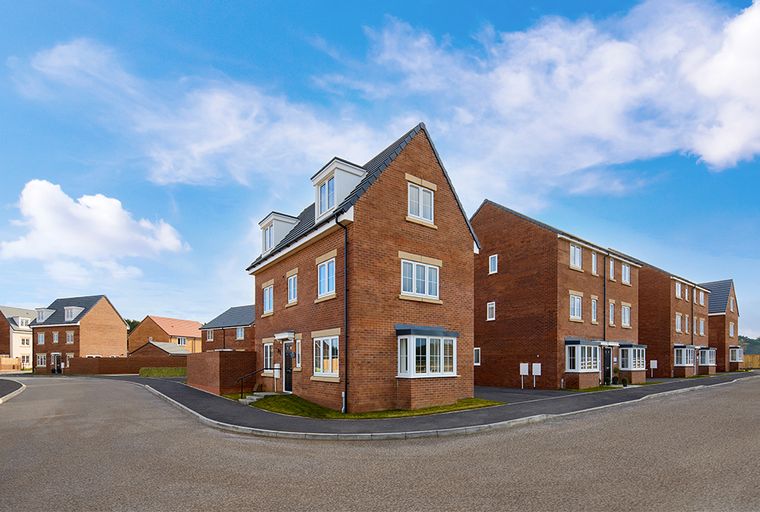 A street view of modern brick townhouses under a blue sky with clouds.