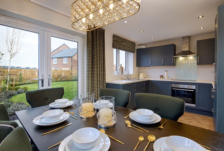 A dining room and kitchen area with a table set for a meal and modern cabinetry.