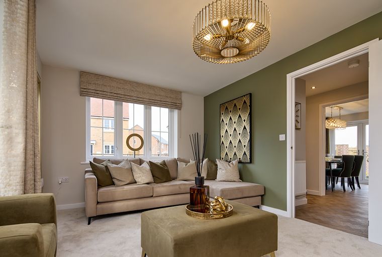 A living room with a sectional sofa, ottoman, and a large window.