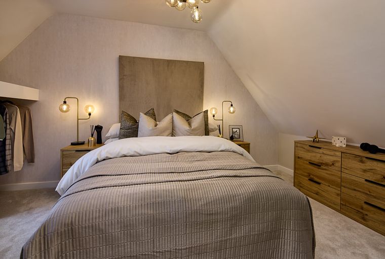 A bedroom with a bed, headboard, bedside tables, lamps, and a dresser.