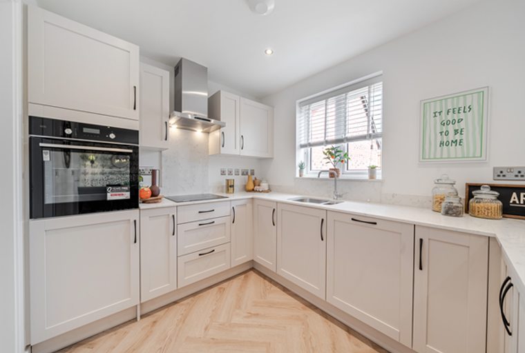A modern kitchen with cream cabinets, a built-in oven, and a stainless steel extractor hood.