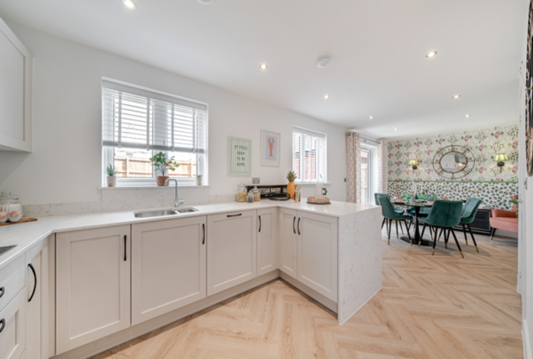 A kitchen and dining area with white cabinets, a kitchen island, and a dining table with green chairs.