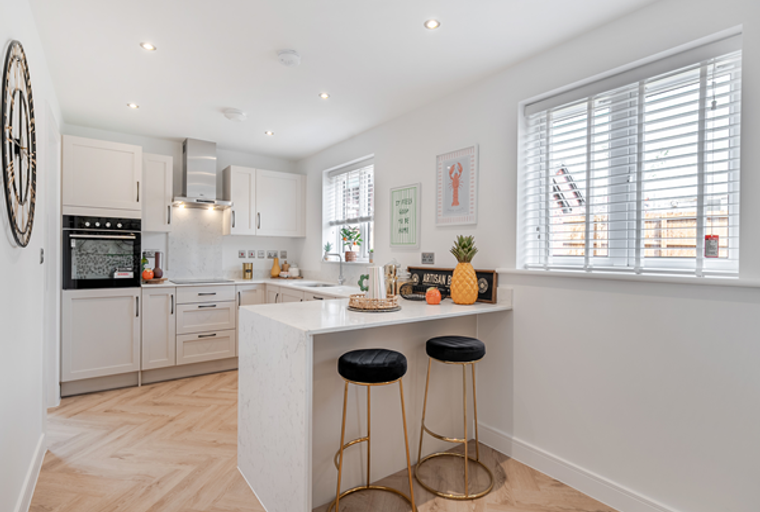 A modern kitchen with cream cabinets, a kitchen island, and bar stools.