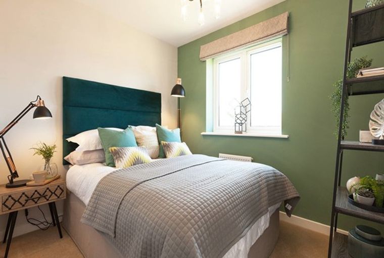 A bedroom with a bed, headboard, pillows, lamps, and a window.