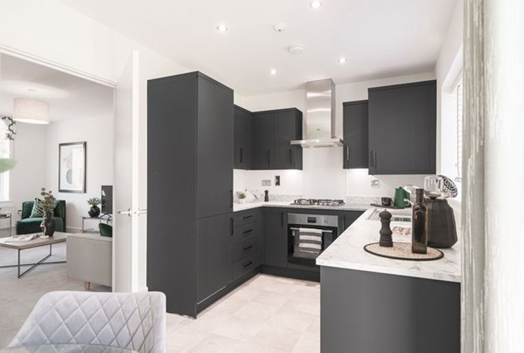 A modern kitchen with dark cabinets, marble countertops, and a stainless steel range hood.