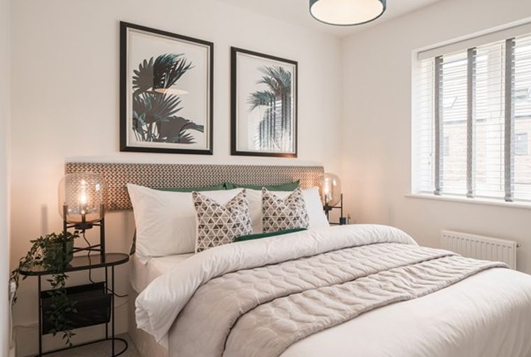 A bedroom with a bed, pillows, artwork, and a window.